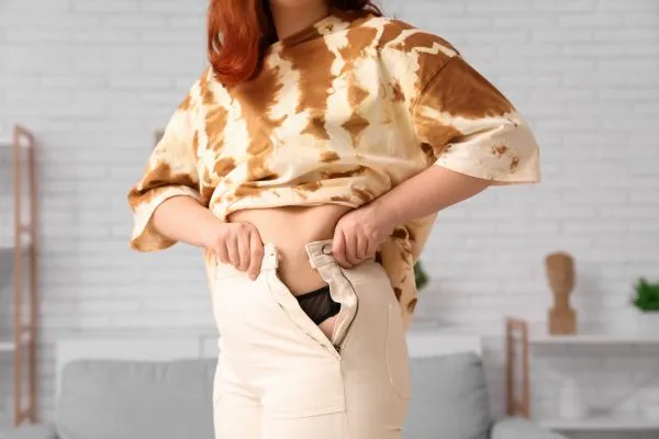 Image of woman trying to do her trousers up after pregnancy weight gain Llanelli